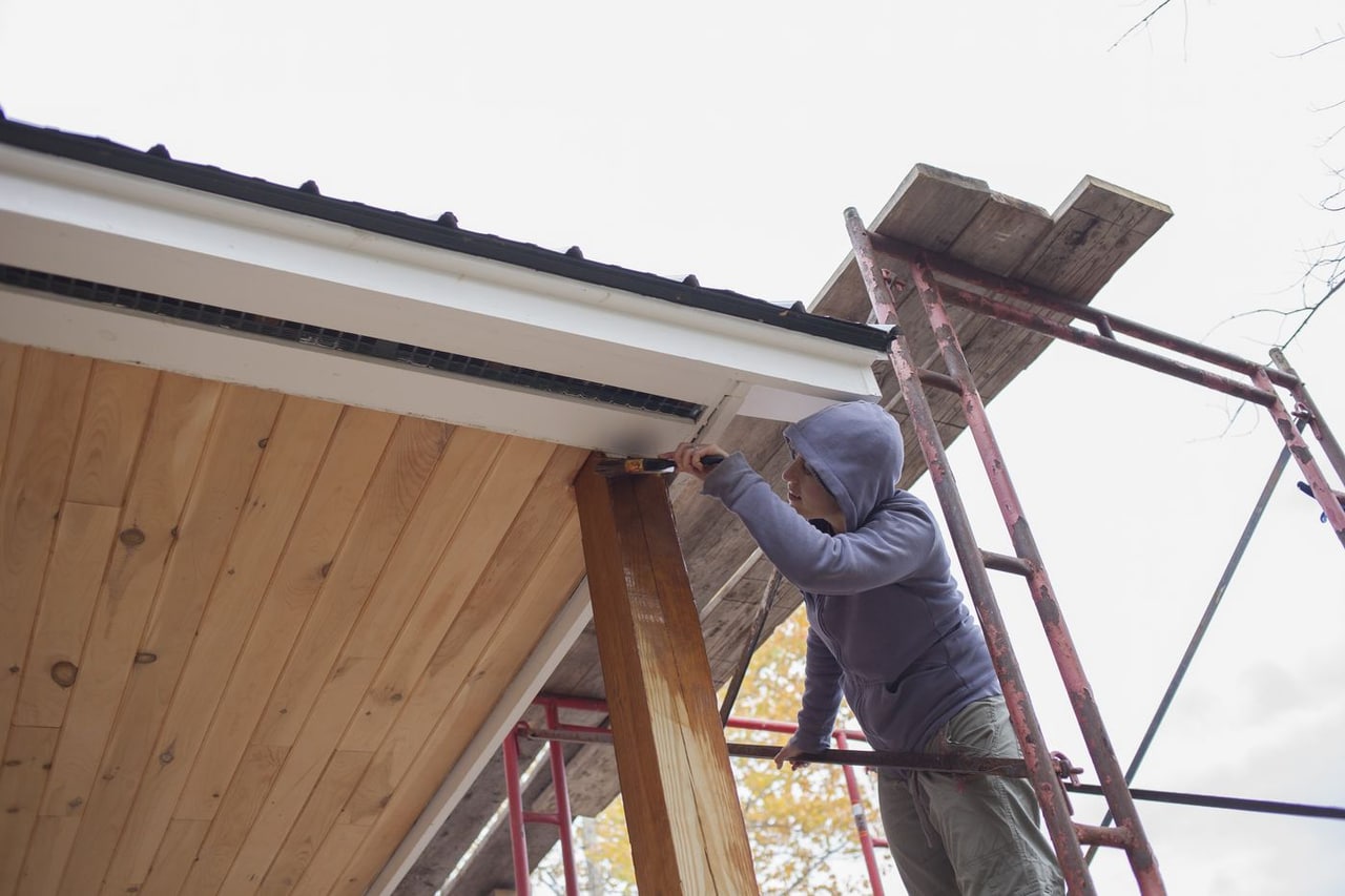 Worker finishing exterior trim at the edge of a roof