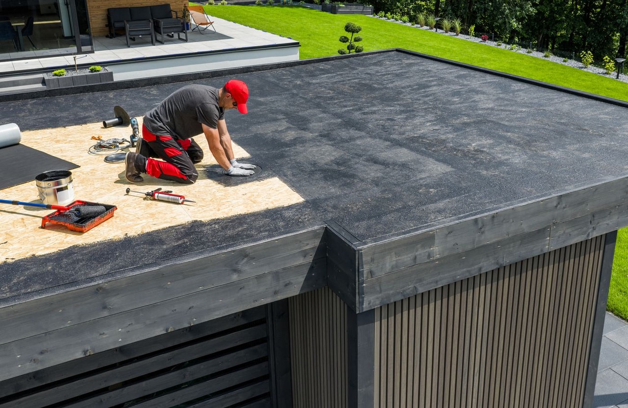 Roofer applying a waterproof membrane on a flat residential roof