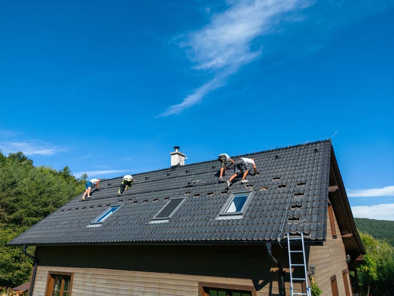 Crew installing new dark roof tiles across the full roof of a house